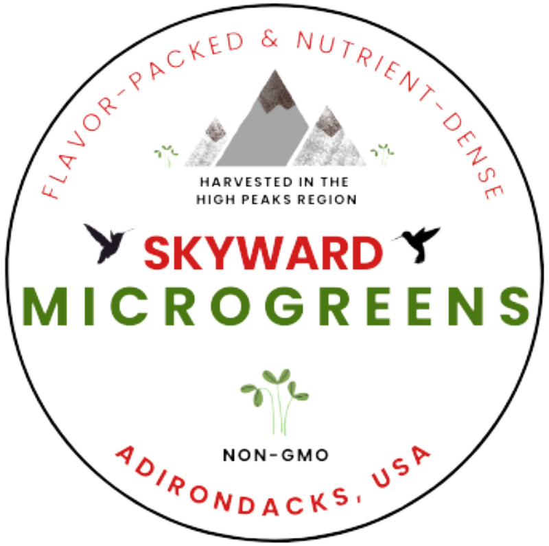 Logo Label for Skyward Microgreens featuring a circular design with mountains, a hummingbird, and text highlighting flavor, nutrient density, and non-GMO status, emphasizing its harvest from the High Peaks region in the Adirondacks, USA.